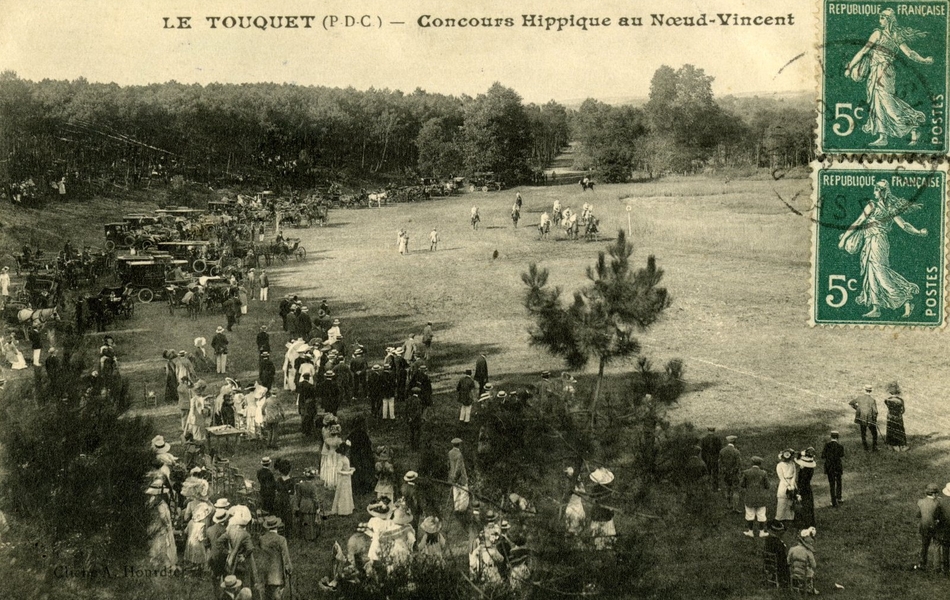 Carte postale noir et blanc d’un champ de courses devant une foule spectateurs au premier plan.