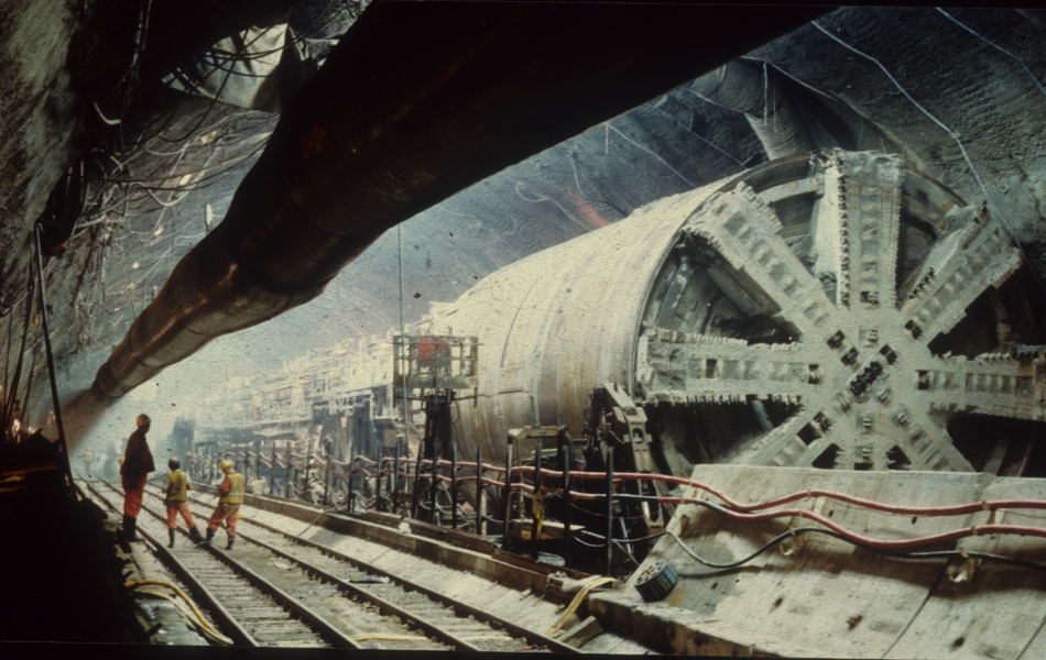 Photographie couleur montrant l'intérieur d'un tunnel où l'on voit des machines et des ouvriers.
