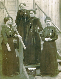 Photographie noir et blanc montrant quatre posant dans un escalier.