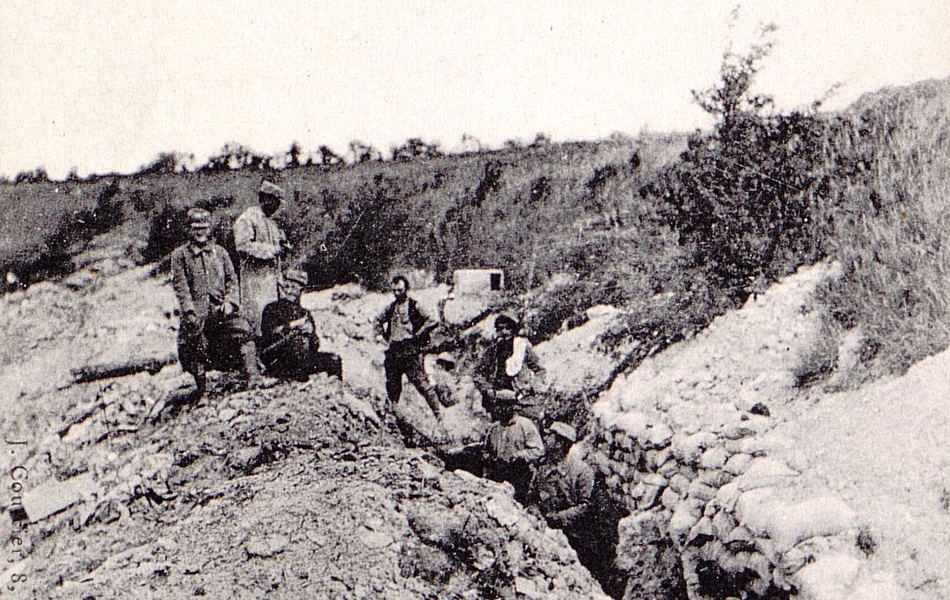 Carte postale noir et blanc montrant des soldats dans une tranchée de faible profondeur.
