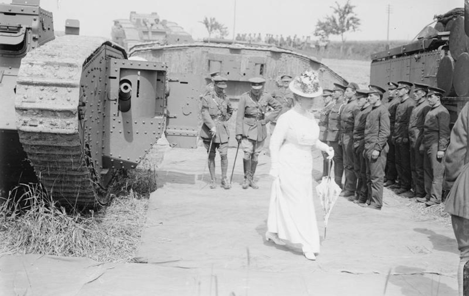 Photographie noir et blanc montrant une femme en robe blanche devant des soldats et des tanks.