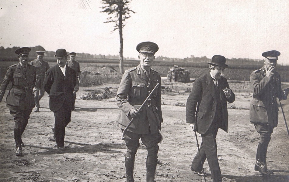 Photographie noir et blanc montrant deux civils entourés de militaires en train de marcher.