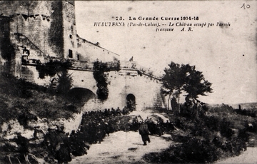 Carte postale noir et blanc montrant un groupe de soldats devant les ruines d'un château. 