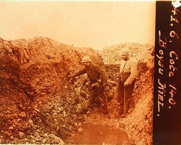 Photographie sepia montrant des hommes dans une tranchée, devant une flaque d'eau.