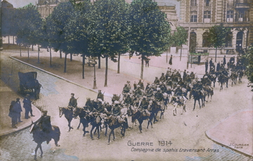 Carte postale noir et blanc montrant des cavaliers traversant une rue pavée.