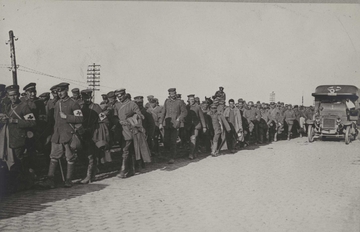 Photographie noir et blanc montrant un convoi d'hommes marchant le long d'une route.
