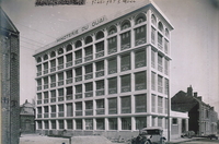 Photographie noir et blanc d'un bâtiment à plusieurs étages sur lequel on lit "Minoterie du quai".