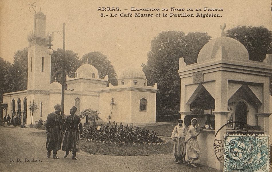 Carte postale noir et blanc montrant un bar extérieur à l'architecture orientale au premier plan; trois enfants y sont rassemblés et regardent vers le photographe. À l'arrière plan se dessine un bâtiment maure accompagné d'un minaret, d'où s'avancent deux hommes en habit traditionnel.