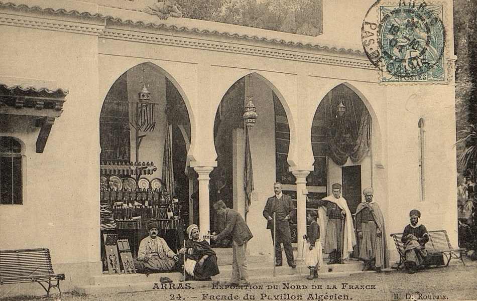 Carte postale noir et blanc montrant la façade d'un bâtiment maure devant laquelle sont regroupés des européens et des arabes.