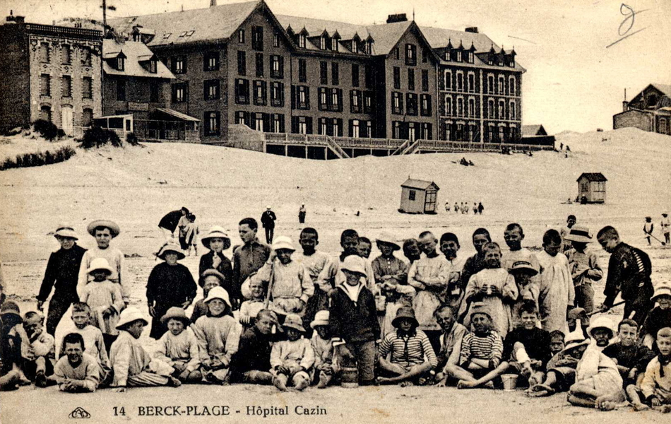 Carte postale noir et blanc montrant un groupe d'enfants sur une plage.