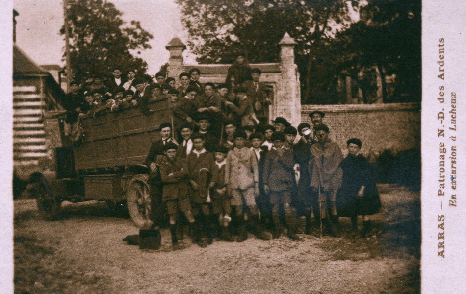Carte postale noir et blanc montrant de jeunes garçons devant et dans un camion.