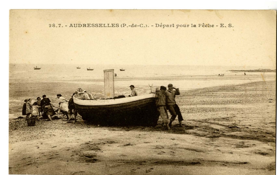 Carte postale en noir et blanc d’une barque sur la plage, tirée et poussée par un groupe de pêcheurs, de femmes et d’enfants vers la mer