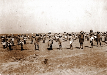 Photographie noir et blanc d'enfants et d'adultes faisant une ronde sur une plage.