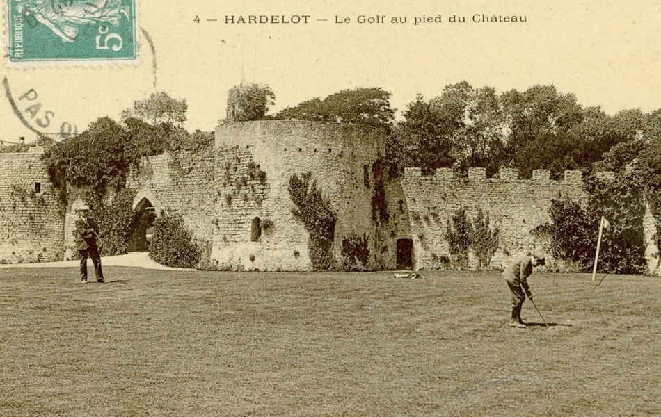 Carte postale noir et blanc d’un green occupé par deux hommes au pied d’un château médiéval.