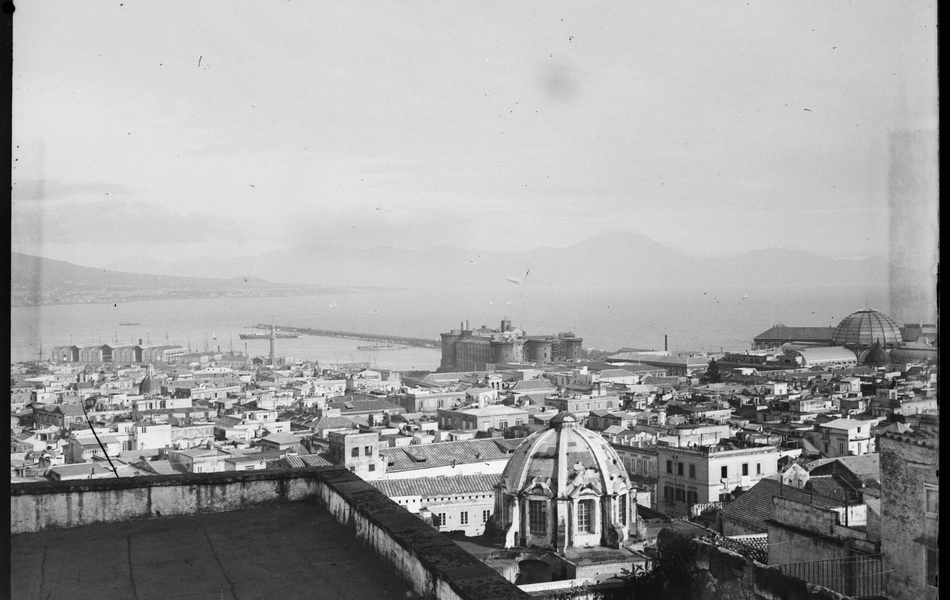 Photographie noir et blanc montrant les toits d'une ville bordée par la mer.
