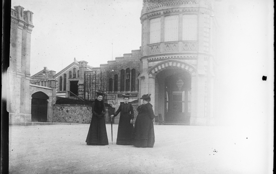 Photographie noir et blanc montrant trois femmes devant un bâtiment.