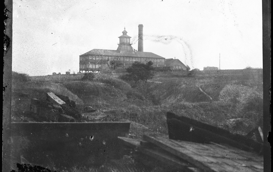 Photographie noir et blanc montrant à l'arrière plan un complexe industriel.