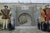 Photographie couleur montrant l'entrée d'un tunnel non creusé, surmontée du logo "Eurotunnel" et "TML". De part et d'autre on reconnaît les représentations de François Ier et Henry VIII. Quelques personnes se pressent autour.