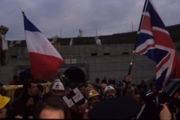 Photographie couleur montrant une foule en liesse portant des drapeaux français et britanniques, devant l'entrée d'un tunnel.