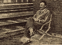 Photographie monochrome de presse montrant un homme assis sur une chaise pliante.