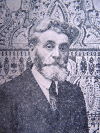 Photographie noir et blanc d'Augustin Lesage qui porte un costume cravate et une barbe très fournie.
