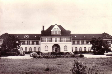 Photographie noir et blanc montrant la façade d'un grand bâtiment.