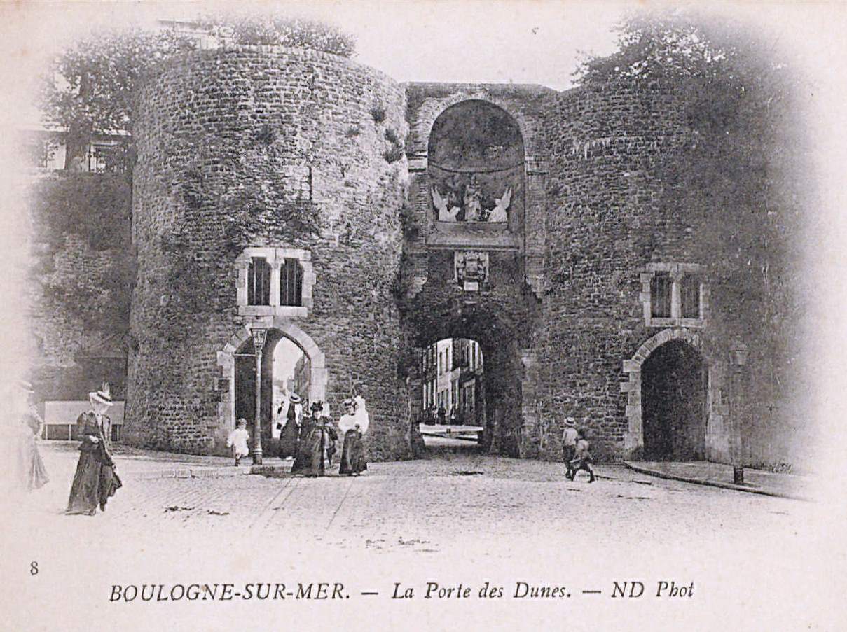 Carte postale noir et blanc montrant une porte de ville flanquée de deux tours médiévales. Au-dessus de l'entrée, on remarque des statues dans une cavité.