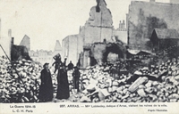 Carte postale noir et blanc montrant un groupe au milieu de ruines et de gravas.