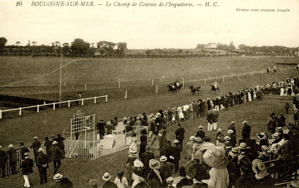 Carte postale noir et blanc d’un champ de courses devant une foule spectateurs au premier plan.