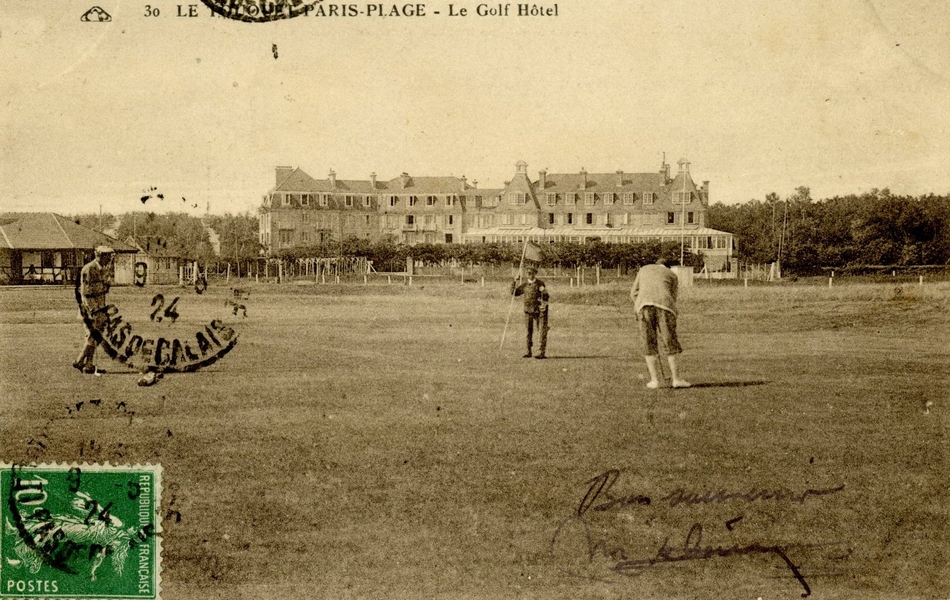 Carte postale noir et blanc d’un green où jouent, au premier plan, trois hommes. Par-derrière, on remarque un grand bâtiment.