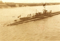 Photographie sepia montrant un sous-marin émergeant de la mer.