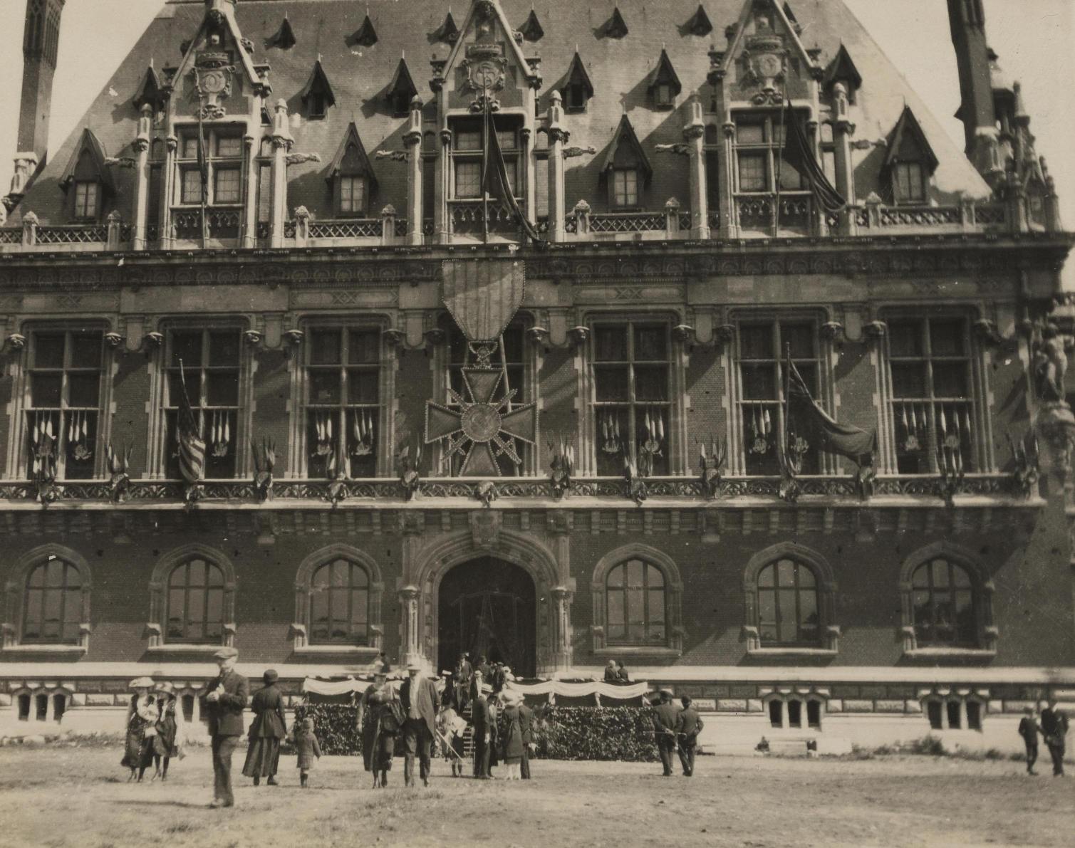 Photographie noir et blanc montrant un bâtiment sur lequel est accroché une croix de guerre.
