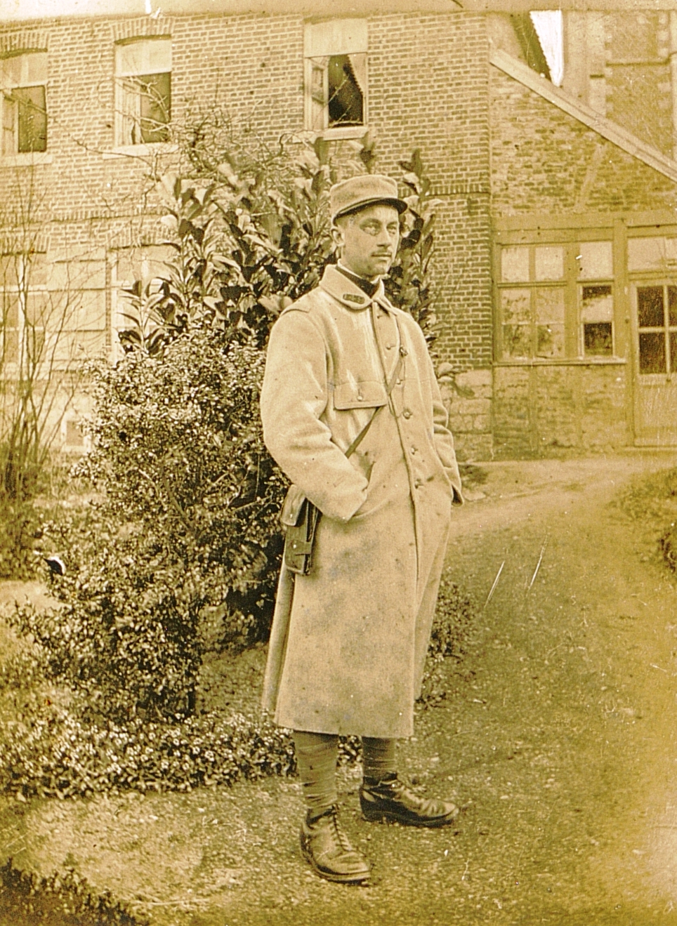 Photographie noir et blanc montrant un soldat debout, vêtu d'un pardessus.