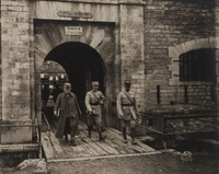 Photographie noir et blanc montrant trois hommes achevant de traverser un pont-levis.