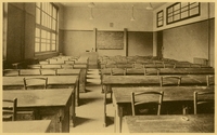 Photographie noir et blanc montrant une classe d'école vide.