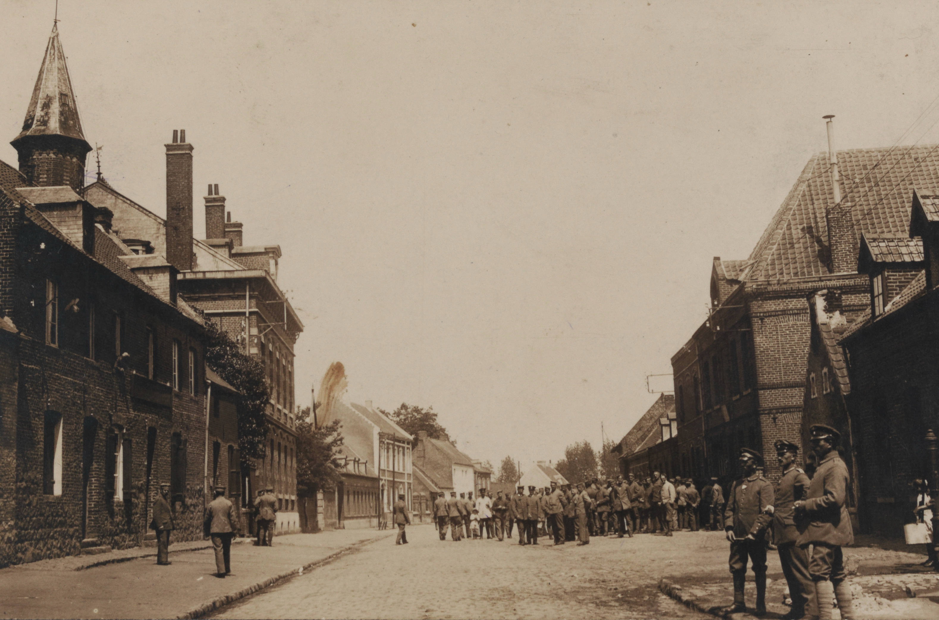 Carte postale noir et blanc montrant des spmdats rassemblés dans une rue.