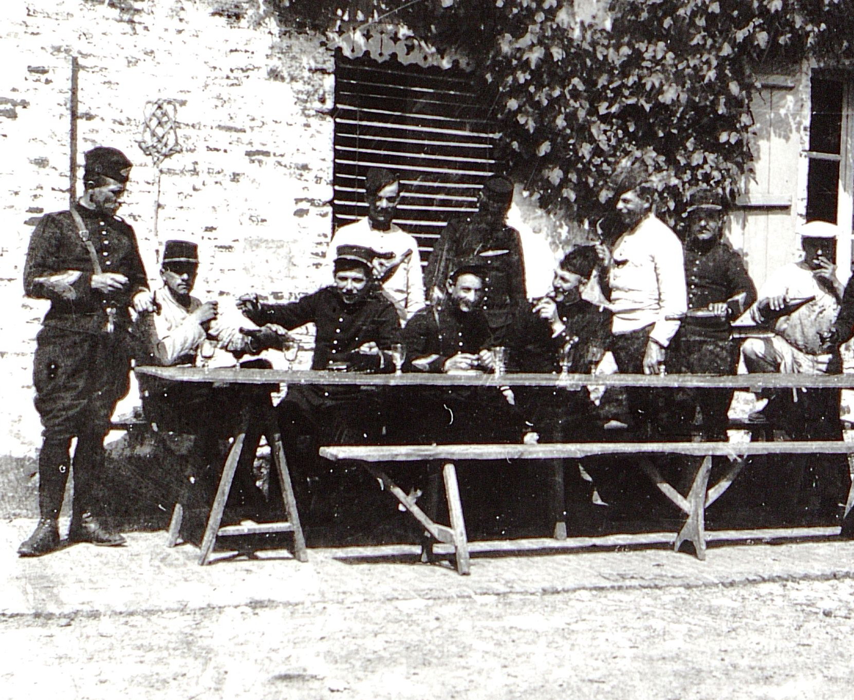 Photographie noir et blanc montrant des militaires attablés en train de se servir des verres de vin.