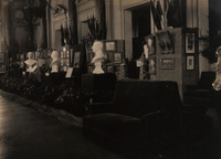 Photographie noir et blanc d'une salle d'exposition de tableaux et de sculptures.