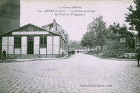 Carte postale noir et blanc montrant un baraquement au coin d'une rue.