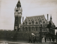 Photographie noir et blanc montrant un beffroi et un grand bâtiment attenant.