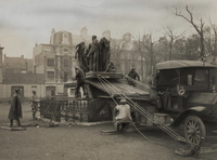 Photographie noir et blanc montrant des hommes en train de démonter une statue de son socle et de la hisser sur un camion.