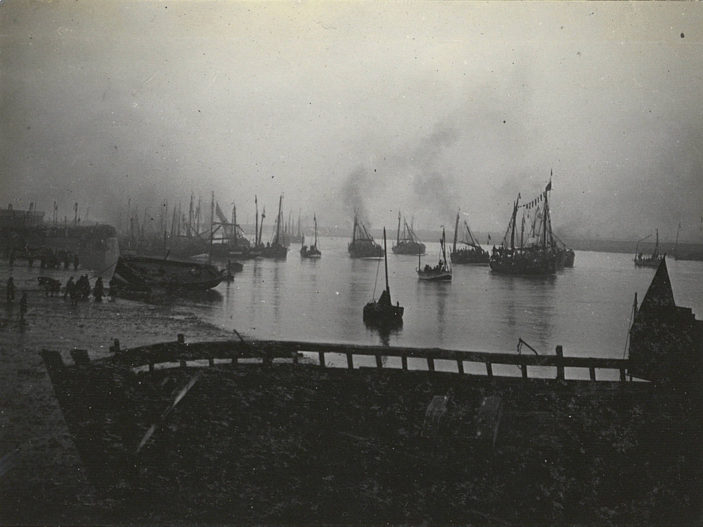 Photographie noir et blanc montrant des bateaux quittant un port.