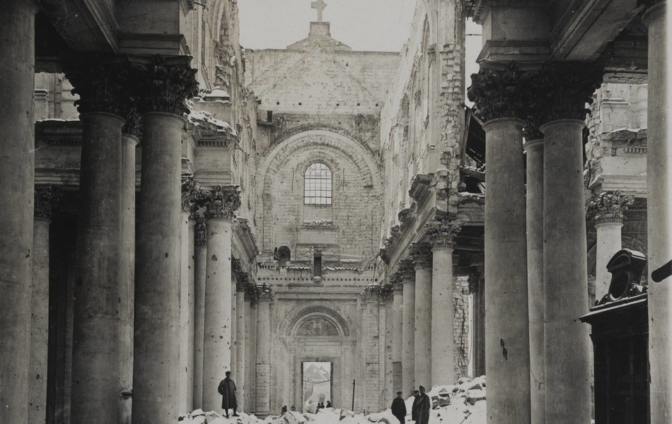 Photographie noir et blanc montrant une cathédrale éventrée, sans toit, dans laquelle la neige a déposé une couche. Des soldats posent dans ces ruines.
