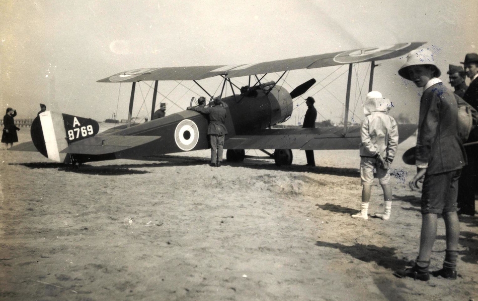 Photographie noir et blanc montrant un groupe de personnes autour d'un avion sur une plage.