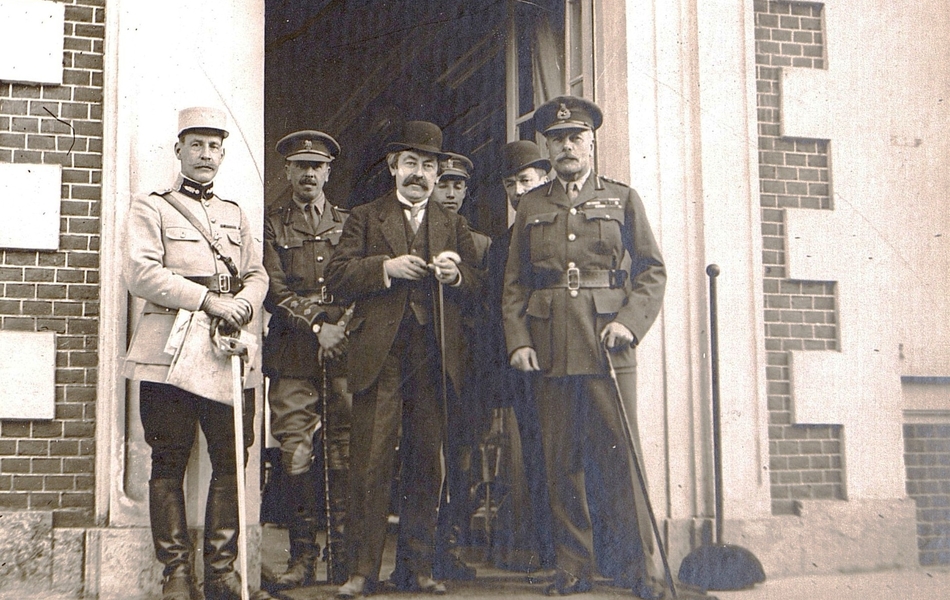 Photographie noir et blanc montrant six hommes debouts sur le perron d'un château. Au premier plan, deux militaires encadrent un civil.