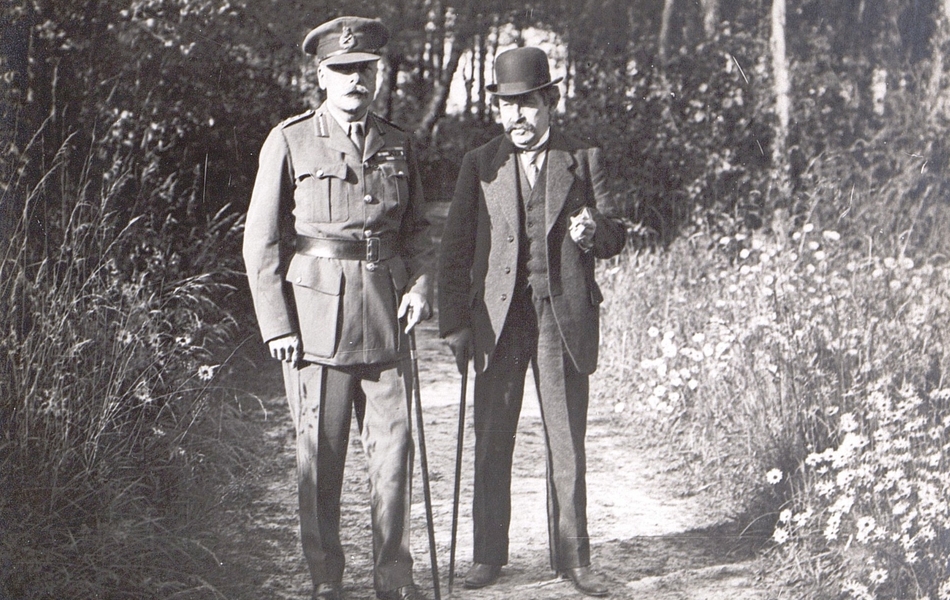 Photographie noir et blanc montrant un militaire et un civil marchant dans l'allée d'un parc.