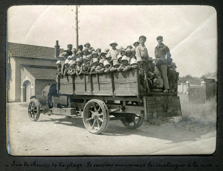 Photographie noir et blanc montrant des enfants amassés dans un camion.
