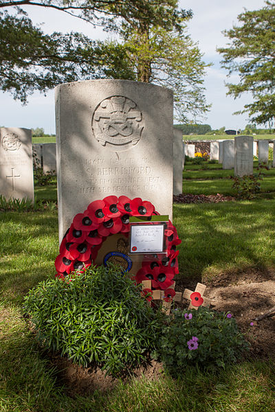 Photographie couleur montrant une tombe militaire décorée d'une couronne de coquelicots.
