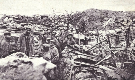 Carte postale noir et blanc montrant des soldats allemands dans une tranchée consolidée par des sacs de terre.