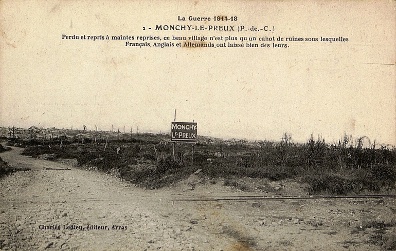 Carte postale noir et blanc d'une plaine. Devant, un écriteau sur lequel on lit "Monchy-le-Preux".